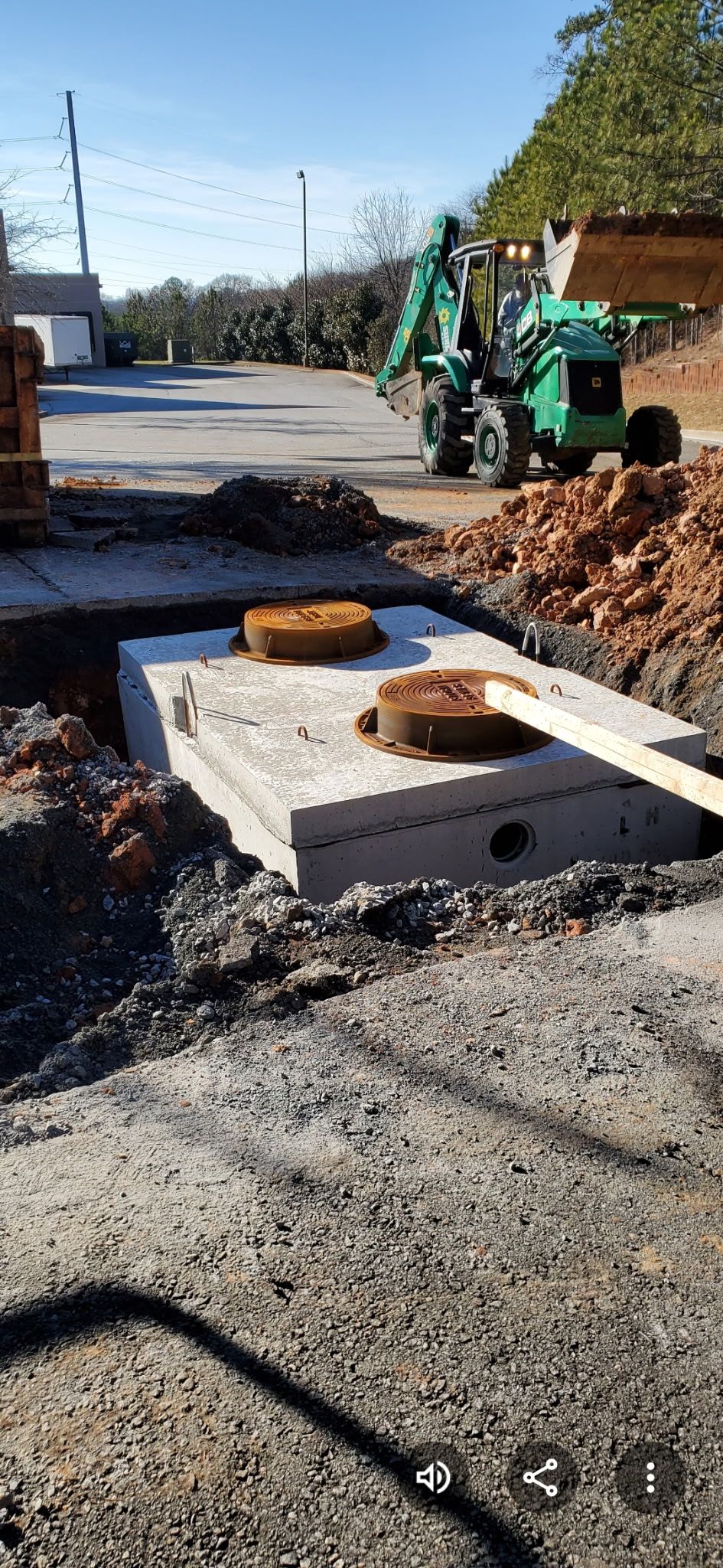 A worker in a hard hat and protective gear inspects pipes and machinery in an industrial setting.