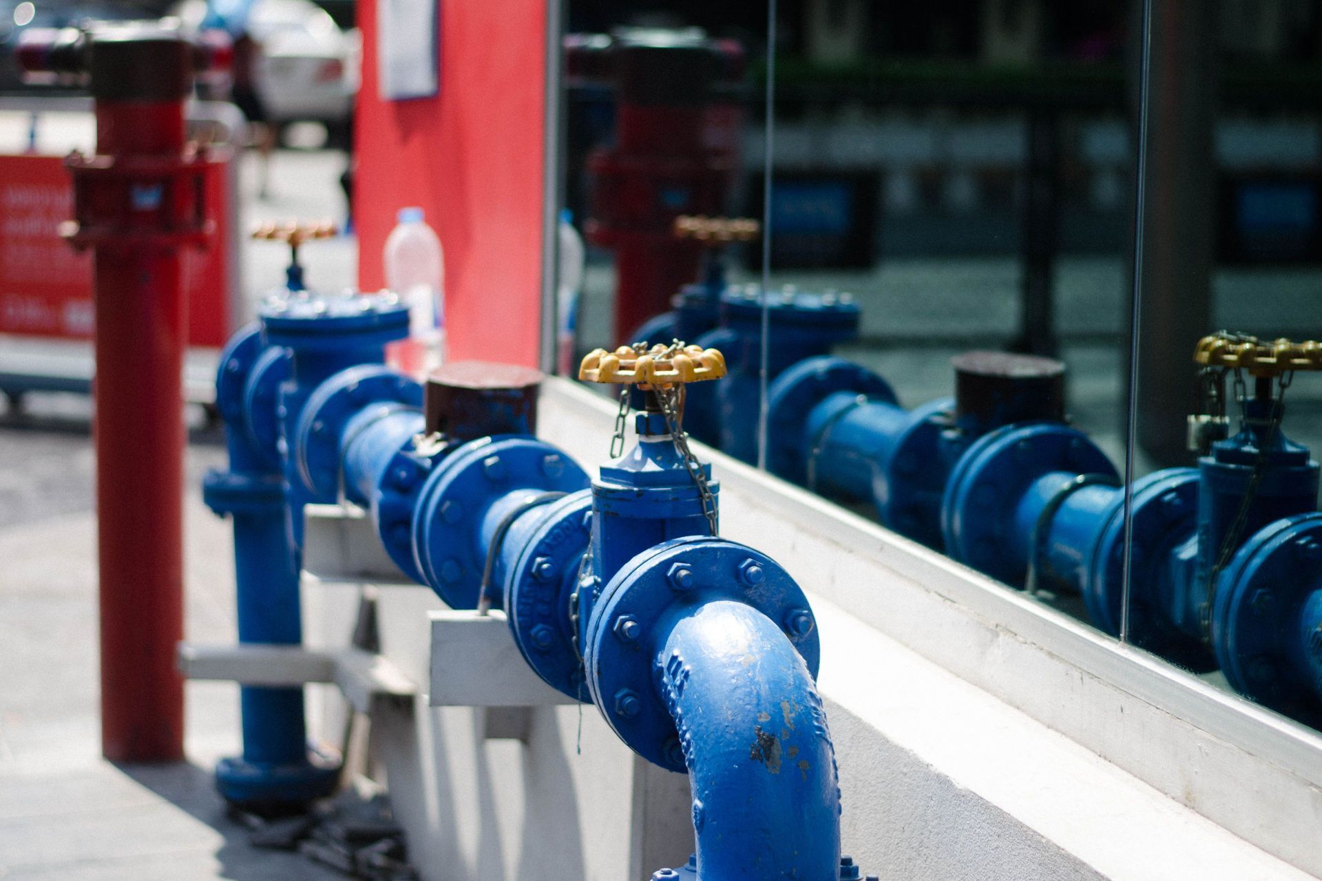 Blue water pipes with gold valves reflected in a window. 