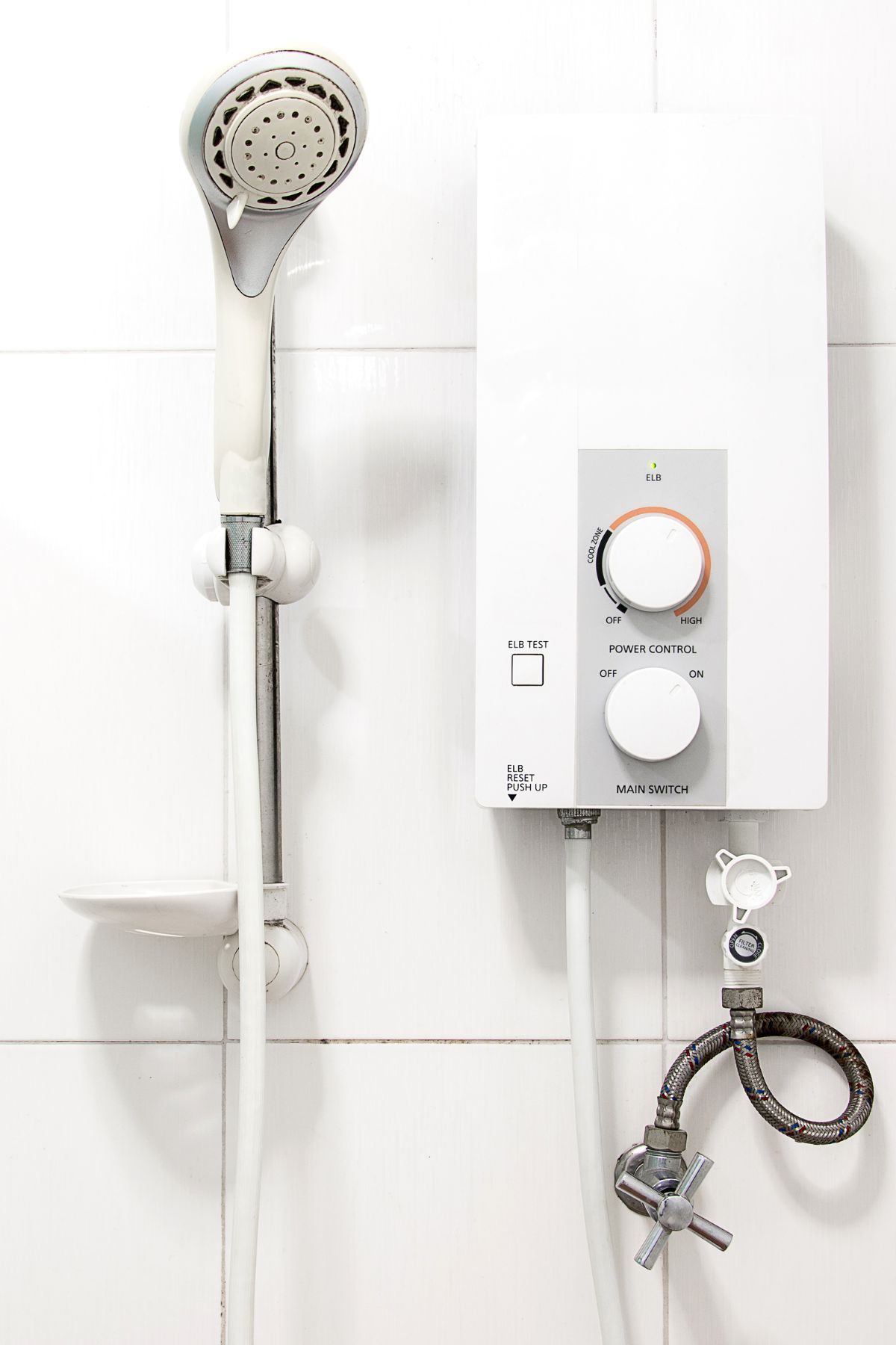 White, cylindrical water heater mounted on a tiled wall in a corner.