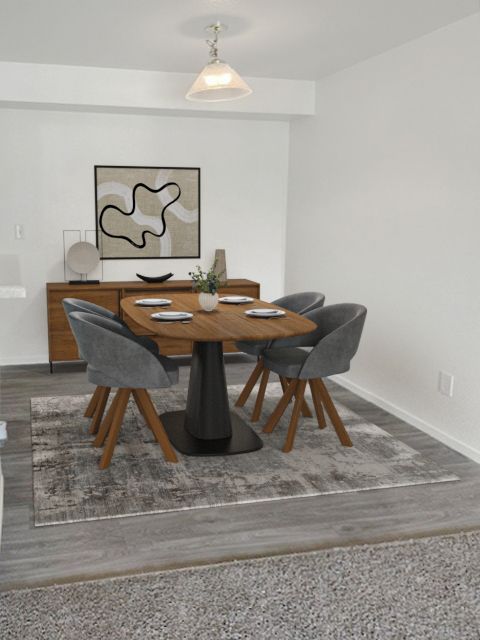 A dining area with a round wooden table, four gray chairs, and a wooden sideboard on a gray patterned rug.