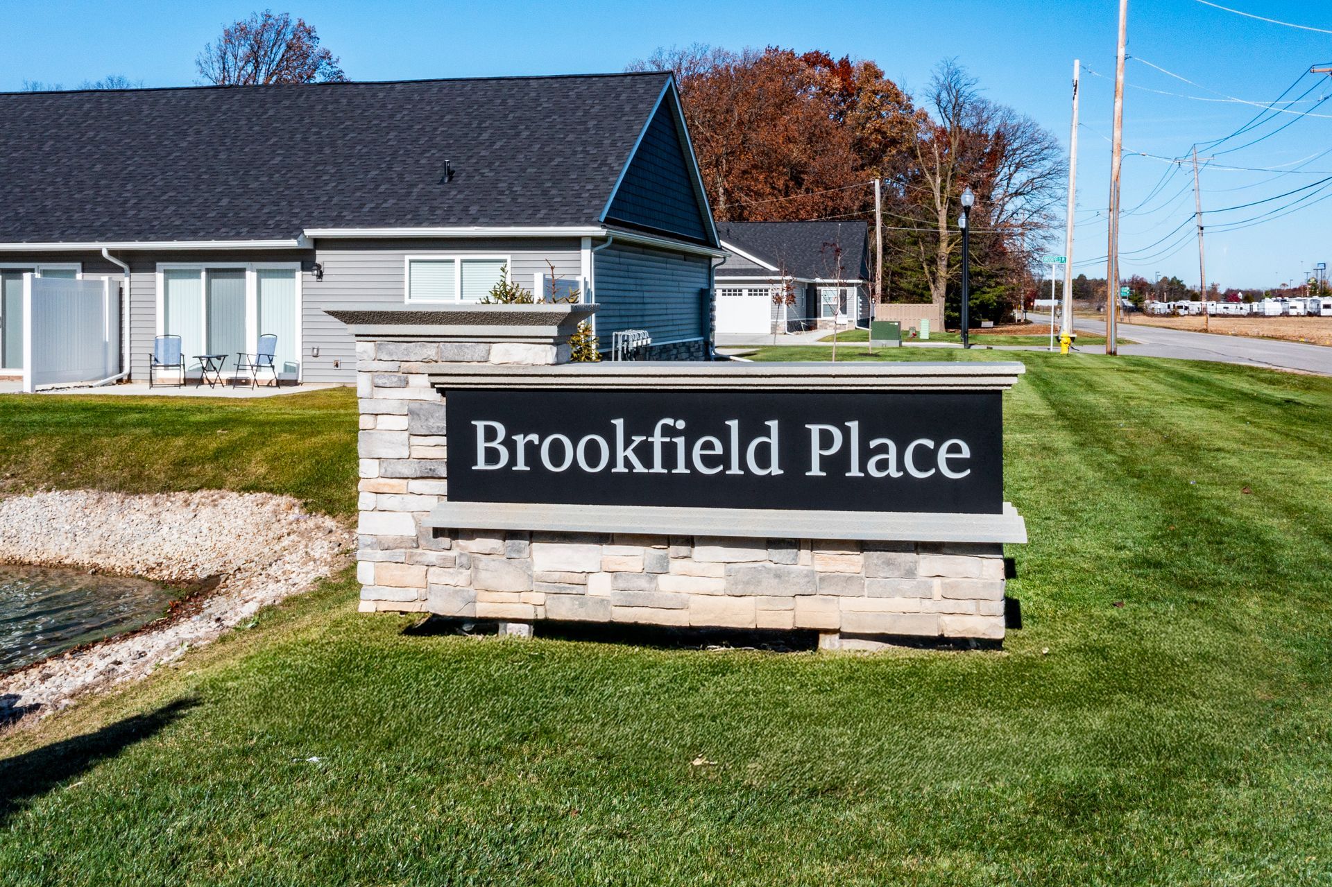 Photo of a sign reading the name of the community, with buildings in the background