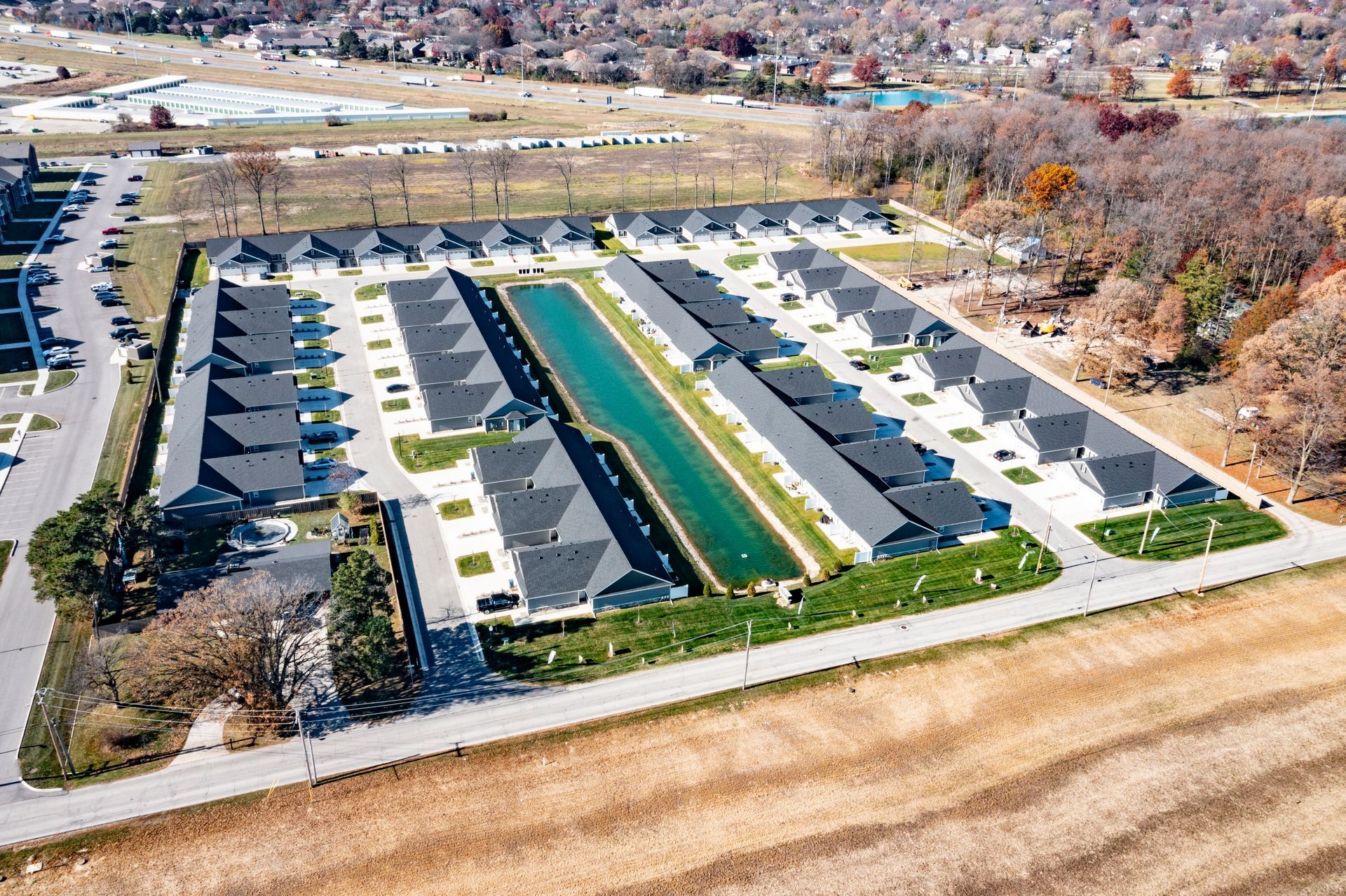 Photo of the community seen from a bird's eye view, showing rows of duplexes with a small body of water in the backyards of some