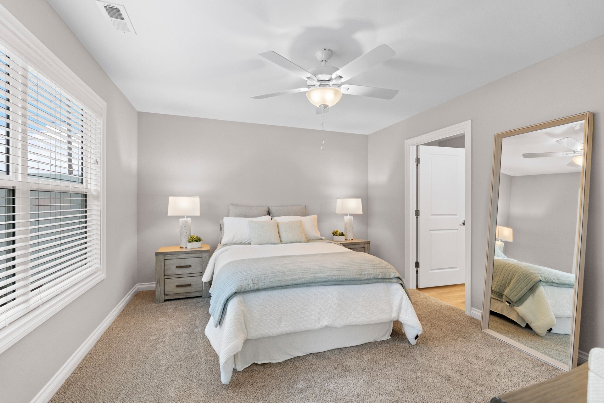Photo of a bed in a bedroom with plenty of natural light and an entrance to the bathroom