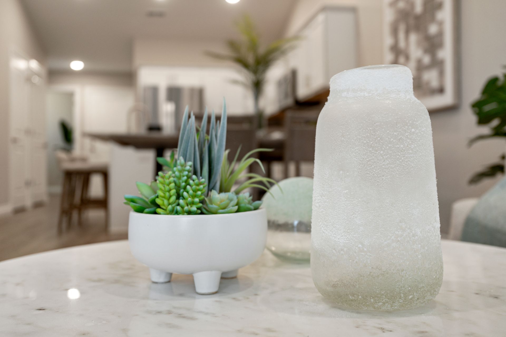 Closeup photo of a few decorations upon a table and a blurred kitchen and dining area in the background