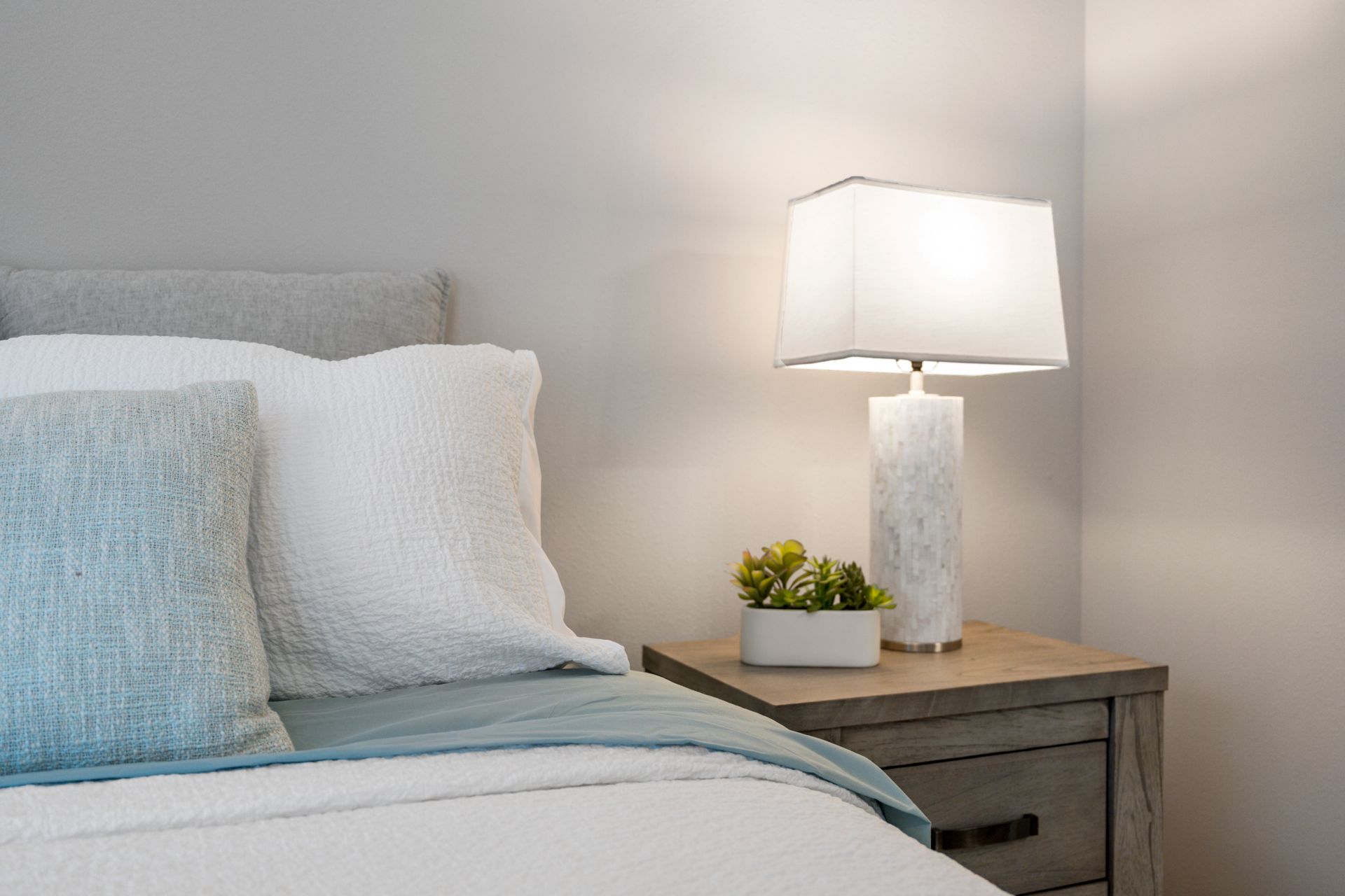 Close up photo of a bed with a nightstand