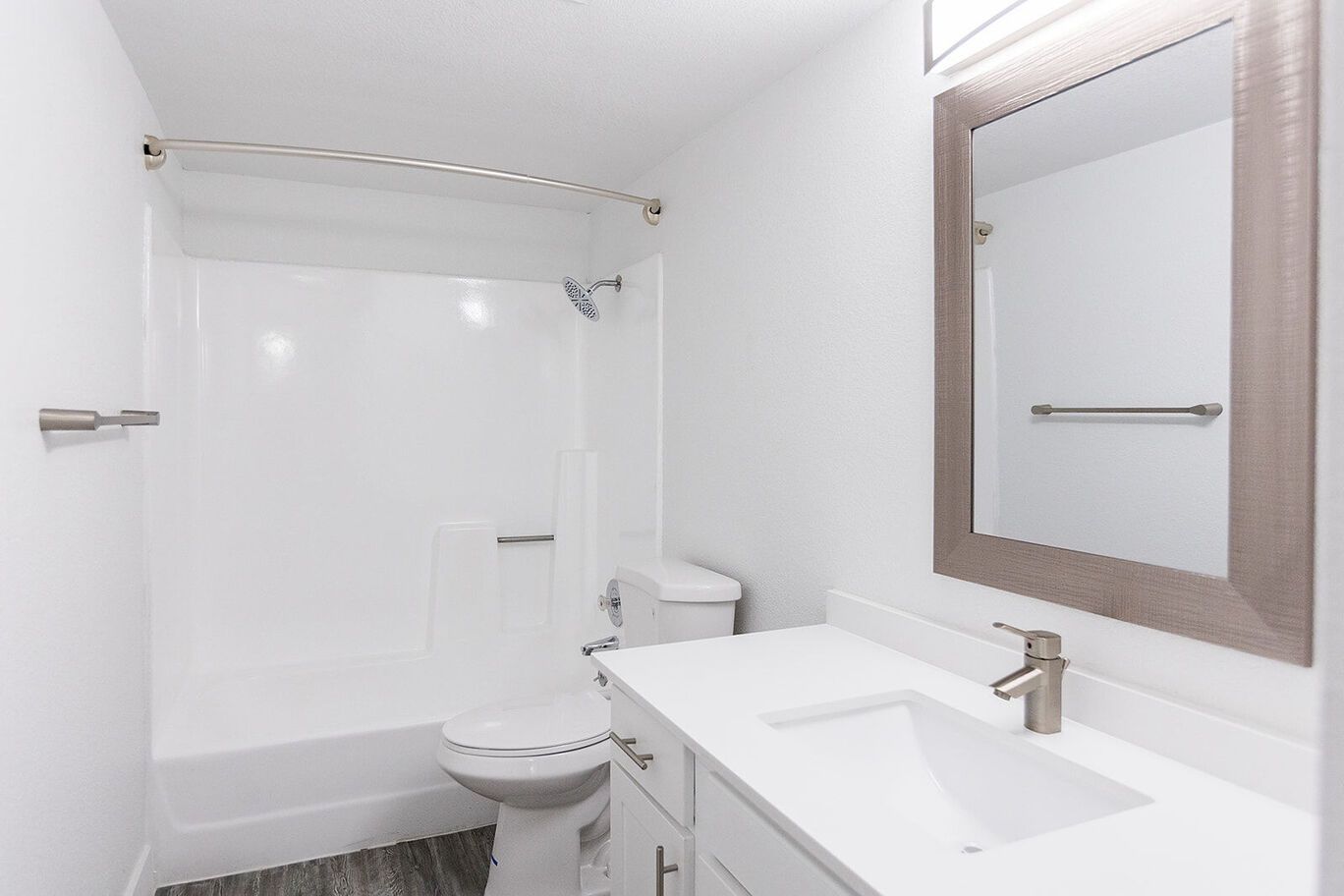 White bathroom with a vanity, toilet, and shower/tub combo.