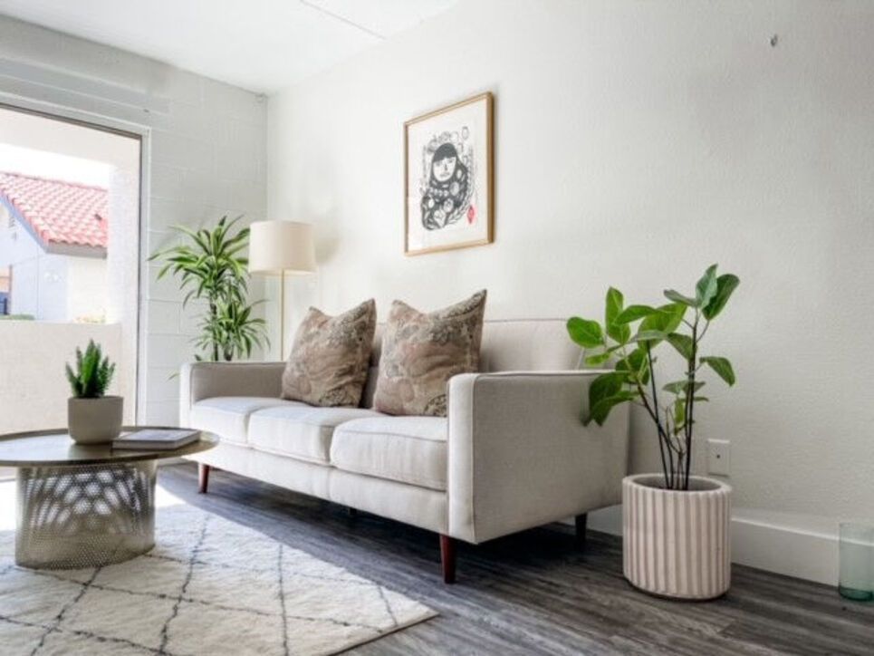 A modern living room with a sofa, plants, and a round coffee table, in neutral colors.