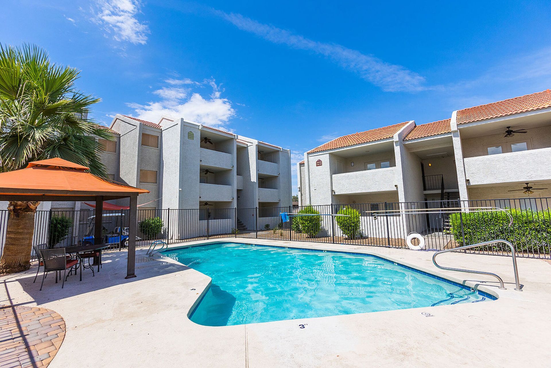 Apartment complex with pool, gazebo, and blue sky.