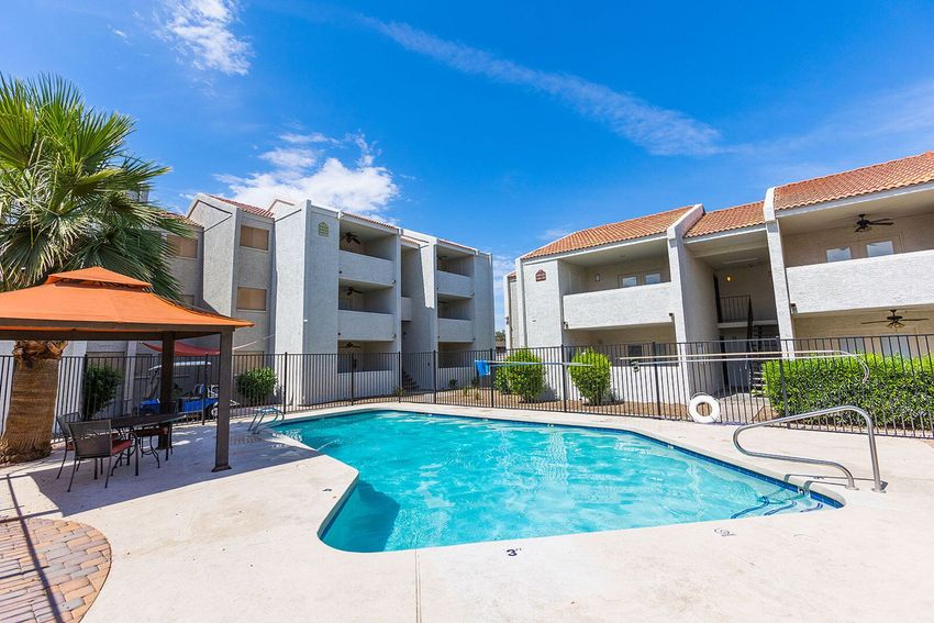 Apartment complex with pool, gazebo, and blue sky.