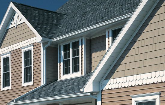 Beige and brown house exterior with dark gray roof, white trim and windows.