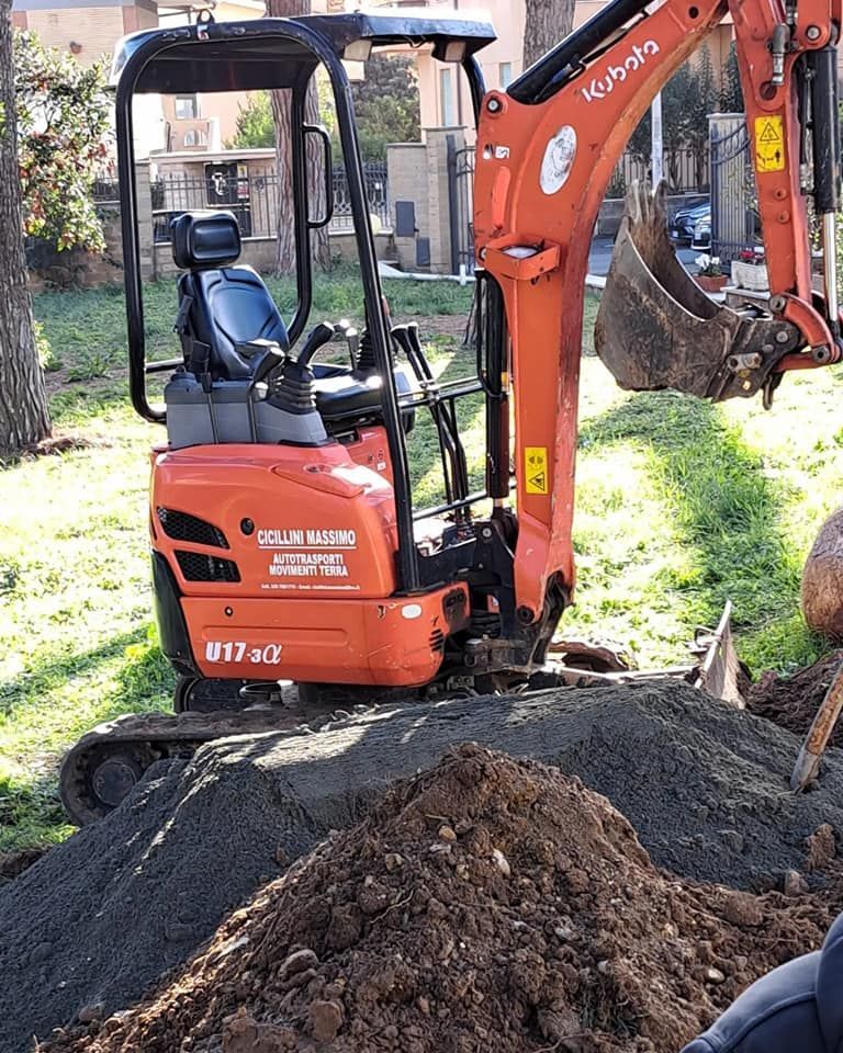 Miniescavatore arancione Kubota U17-3 che scava in un cortile.