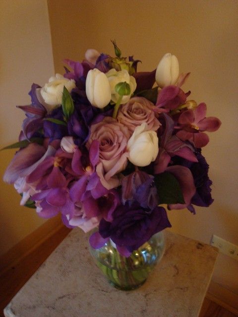 A vase filled with purple and white flowers sits on a table