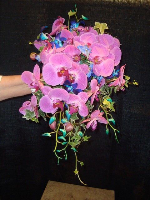 A person is holding a bouquet of pink and blue flowers