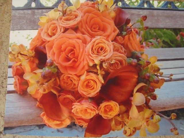 A bouquet of orange roses sits on a wooden bench