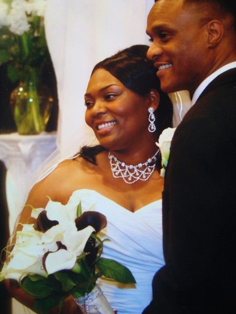A bride and groom are posing for a picture at their wedding