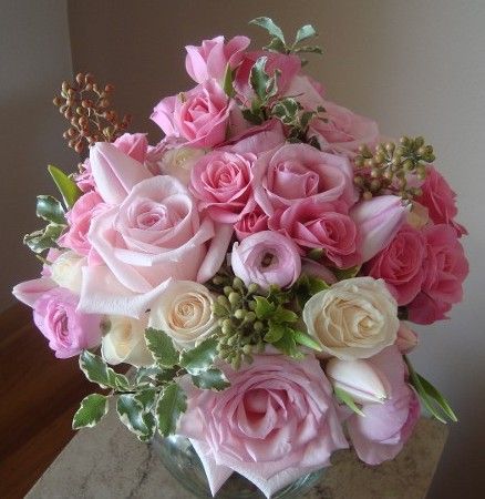 A vase filled with pink and white roses sits on a table