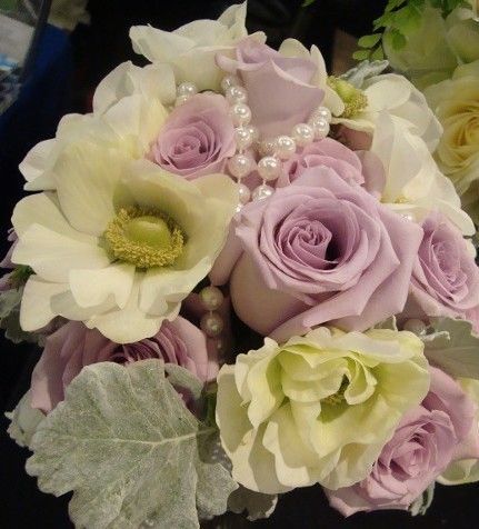 A bouquet of white and purple flowers with a pearl necklace