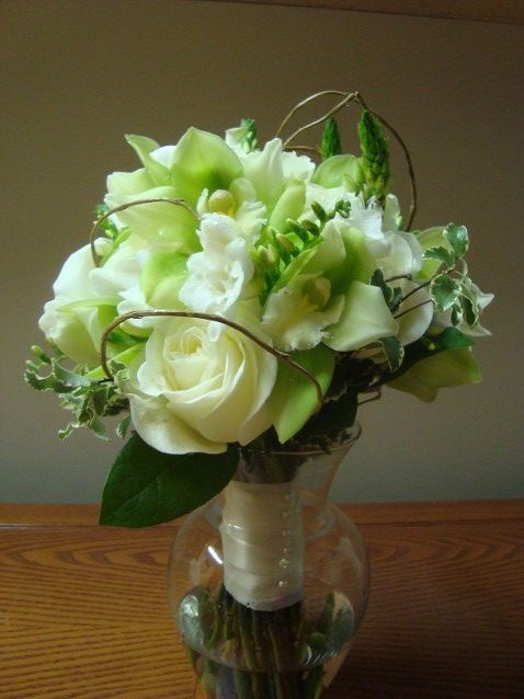 A vase filled with white roses and green flowers