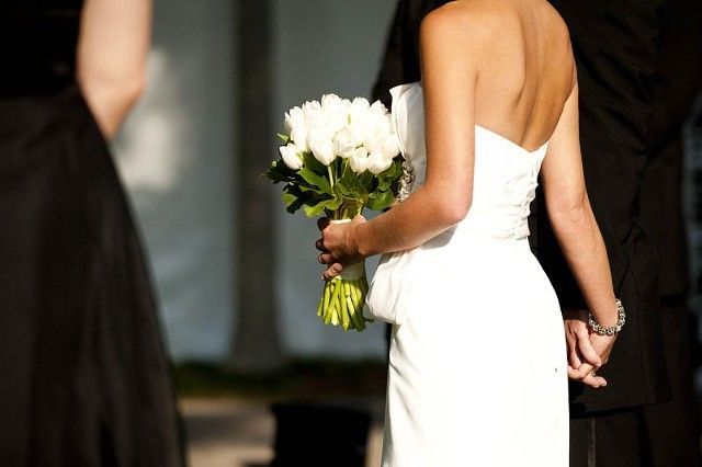 A woman in a white dress is holding a bouquet of white flowers