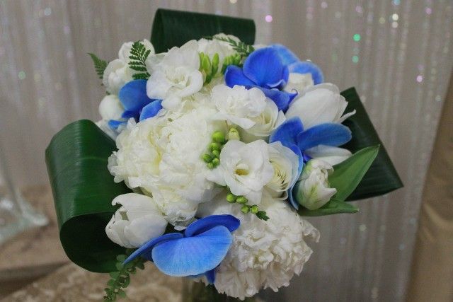 A bouquet of white and blue flowers with green leaves
