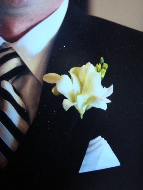A man in a suit has a white flower pinned to his lapel