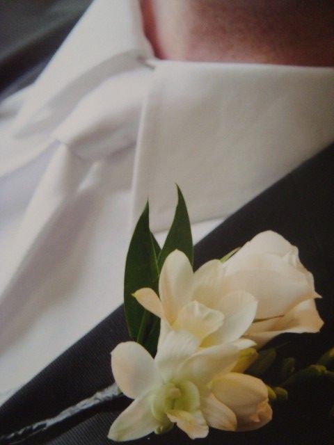 A close up of a white flower on a man 's jacket