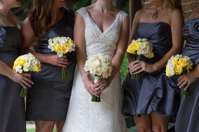 A bride and her bridesmaids are holding bouquets of yellow and white flowers.