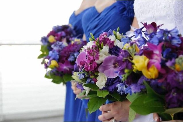 A bride and her bridesmaids are holding bouquets of purple and yellow flowers