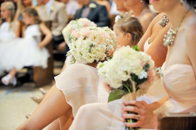A group of women are sitting in a church holding bouquets of flowers.