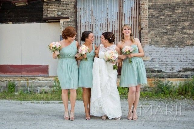 A bride and her bridesmaids are posing for a picture in front of a building.
