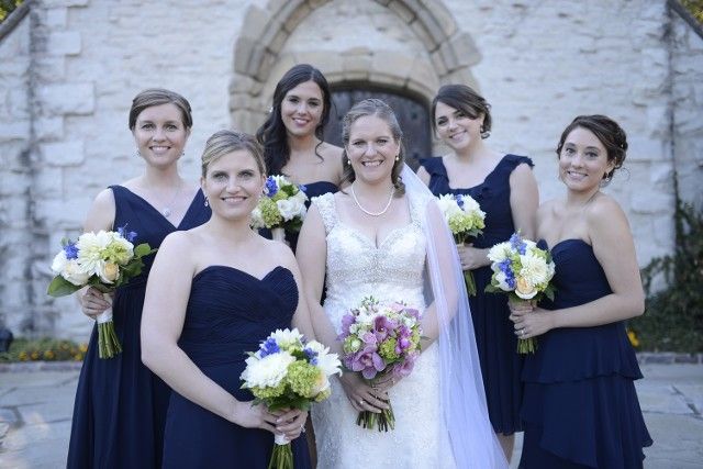 A bride and her bridesmaids are posing for a picture in front of a church.