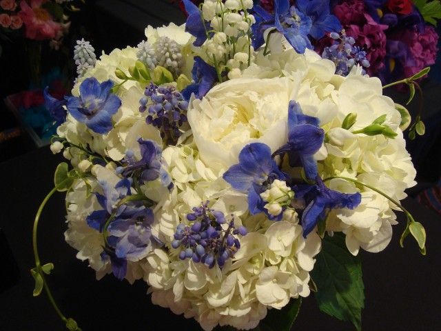 A bouquet of white and blue flowers is sitting on a table.
