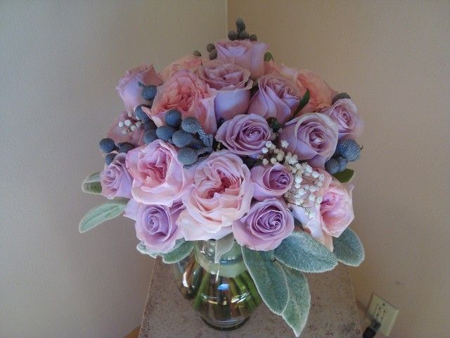 A vase filled with pink roses and blue berries