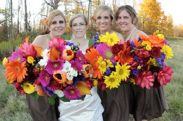 A bride and her bridesmaids are posing for a picture with their bouquets of flowers.