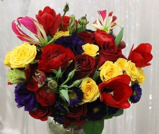 A bouquet of red yellow and purple flowers in a vase