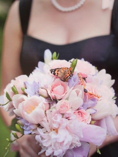 A woman in a black dress is holding a bouquet of pink and purple flowers