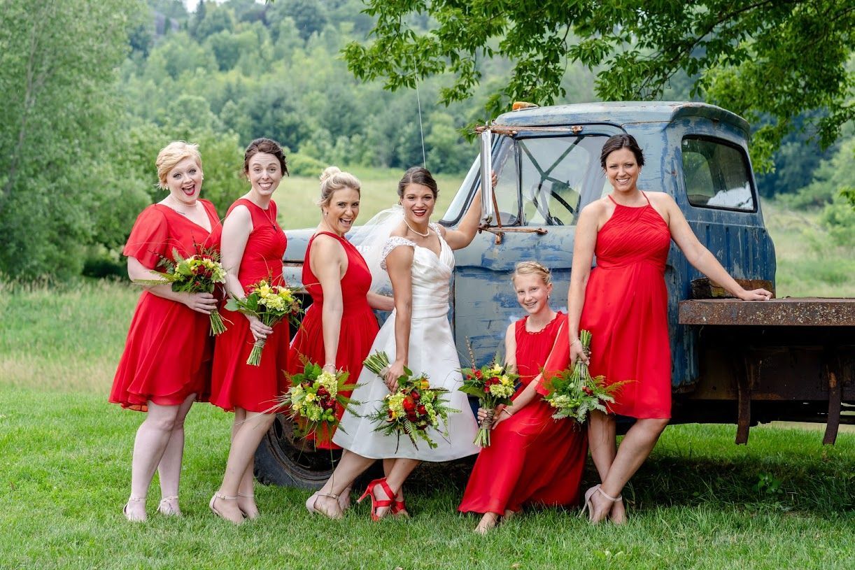 A bride and her bridesmaids are posing for a picture in front of a blue truck.