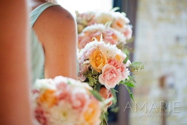 A woman is holding a bouquet of pink and yellow flowers.