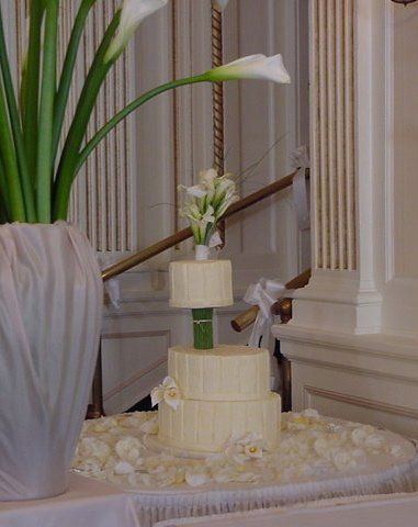 A wedding cake is sitting on a table next to a vase of flowers.