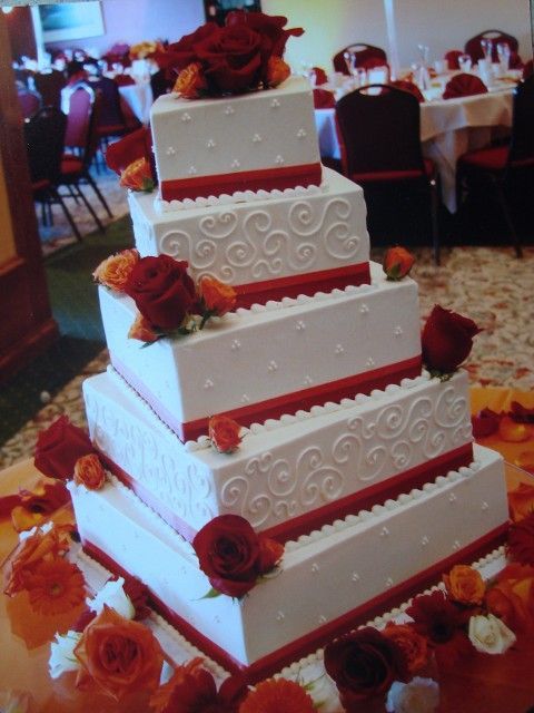 A white wedding cake with red roses on top