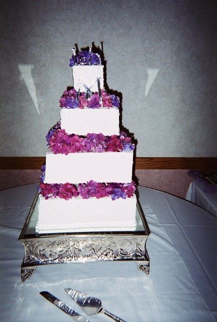 A white wedding cake with purple flowers on it
