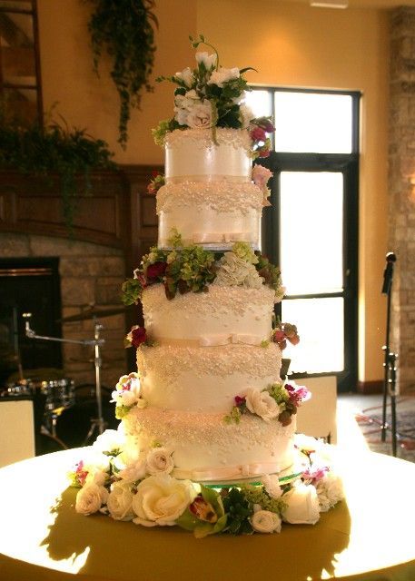 A wedding cake is sitting on a table decorated with flowers