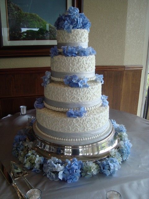 A white wedding cake with blue flowers on top