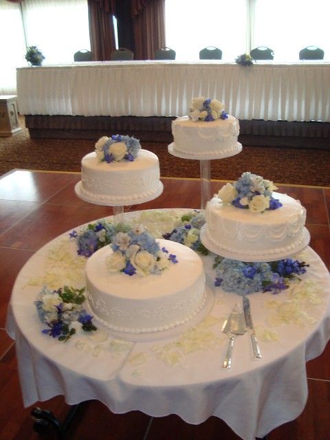 Three wedding cakes on a table with blue flowers