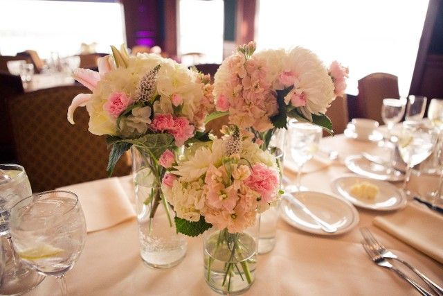 A vase filled with pink and white flowers is on a table.
