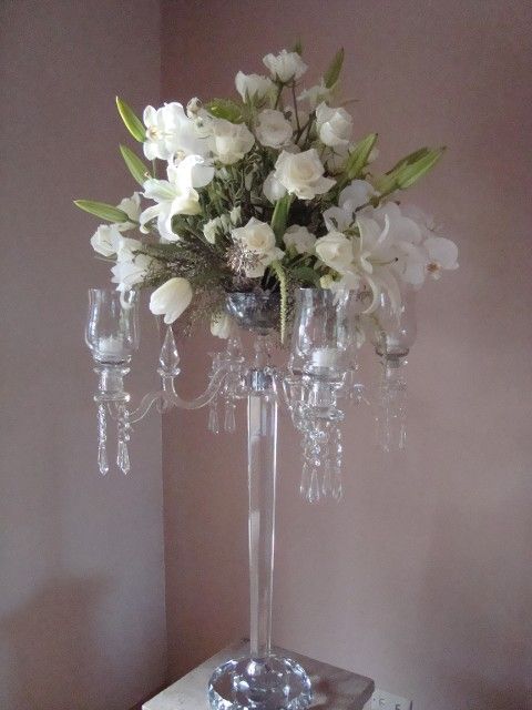 A clear vase filled with white flowers and candles