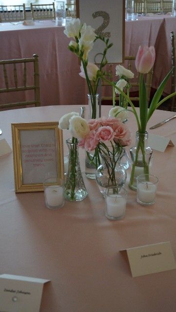 A table with vases of flowers and candles on it