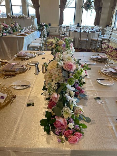 A long table with flowers on it is set for a wedding reception.