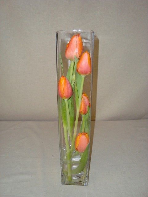 A glass vase filled with orange flowers on a table