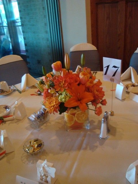 A table with a vase of orange flowers and a table number 17